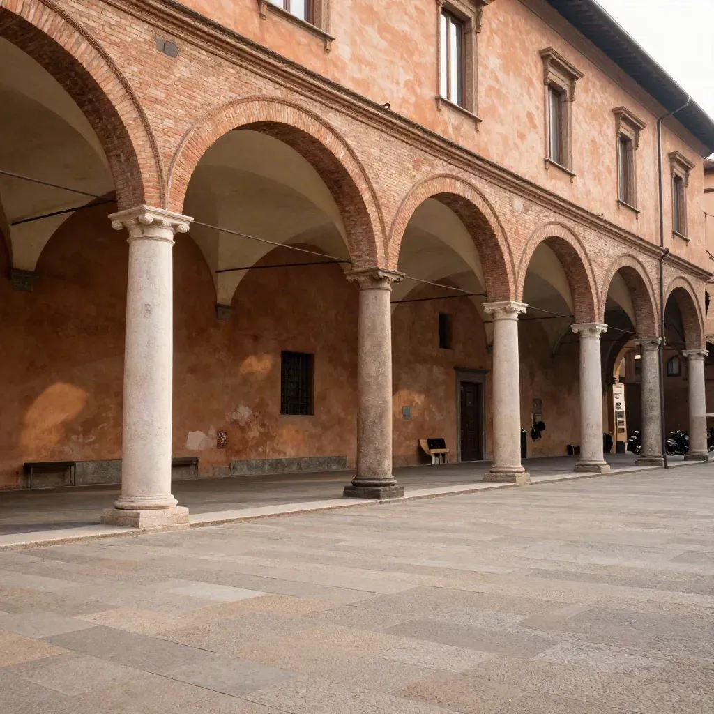 Portici di Bologna in terracotta sopra una piazza chiara e calma, luce calda del tardo pomeriggio.